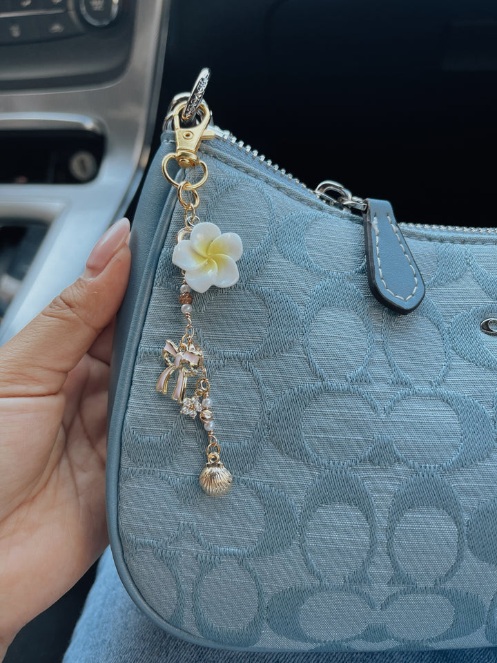 Blue patterned purse with a decorative keychain featuring a flower and bow.