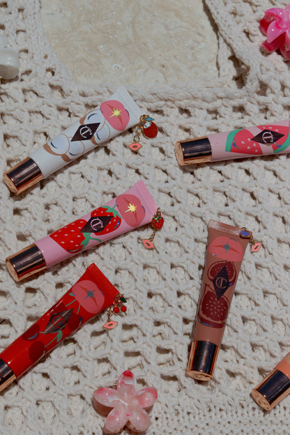 Colorful lip glosses with decorative elements on a textured surface